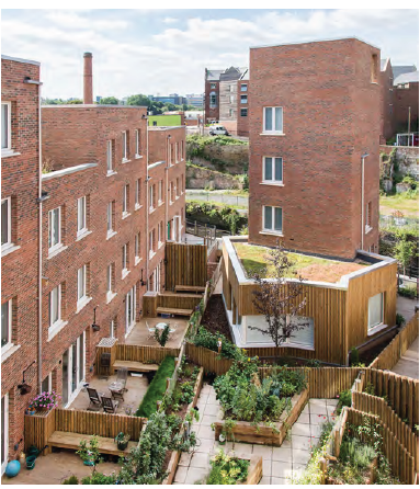 An aerial view of private and communal gardens attached to a residential development of apartments. The private terraces are fenced off and garden furniture is visible in them, while the communal outdoor space features large planters. 