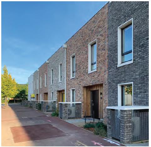 An image of modern terraced housing, with pavement and trees out the front of the buildings.