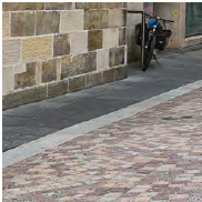 An image of kerb detailing, at the join of cobbles and flat grey paving slabs. 