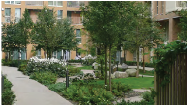 An image showing residential blocks with a central communal open space. The space contains integrated play features and plants. 